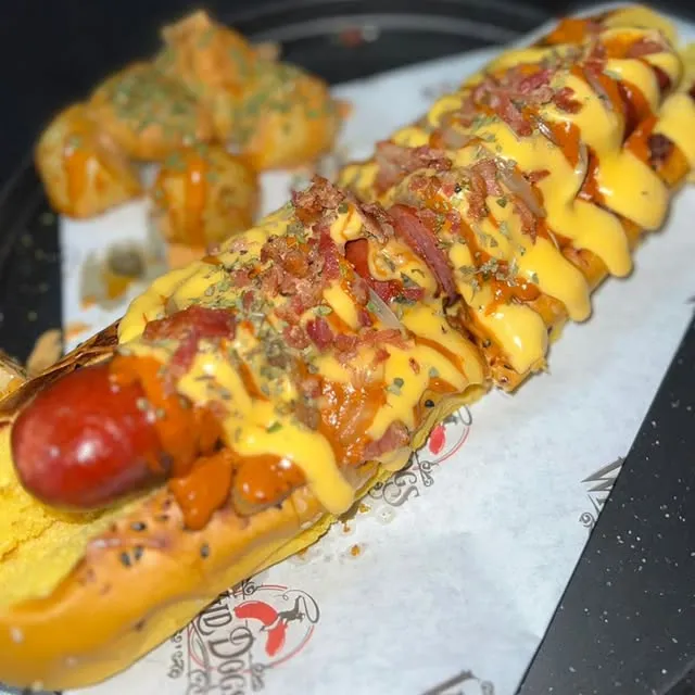 Hot dog con salchicha gruesa, queso cheddar derretido y tocino